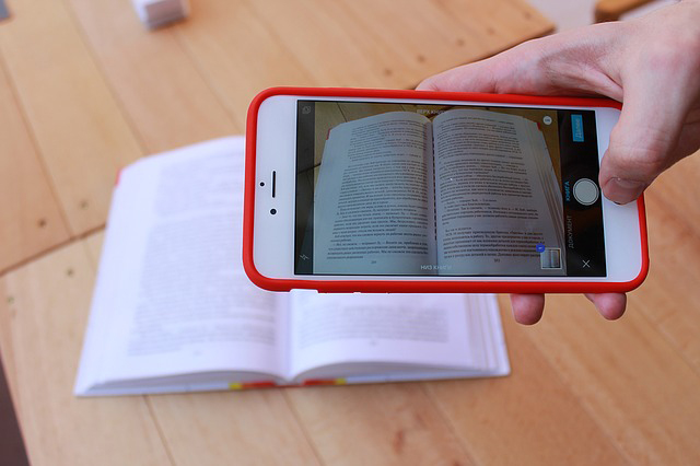 Text on a page in an open book being photographed using a mobile phone
