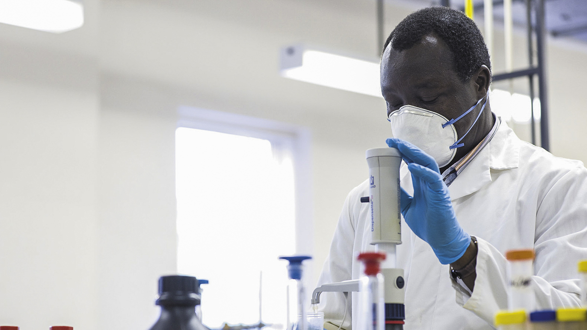 Scientist wearing a face mask and carrying out an experiment