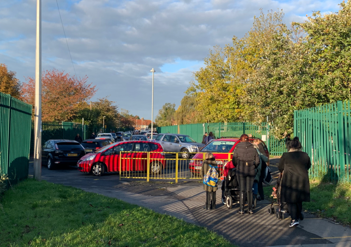 Lots of cars parked outside the entrance of a school