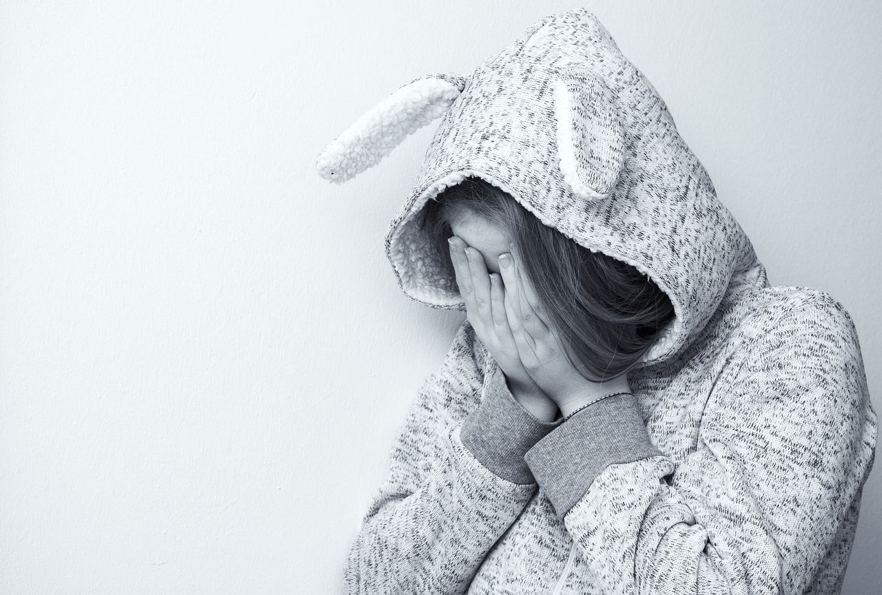 A woman covering her face in sadness