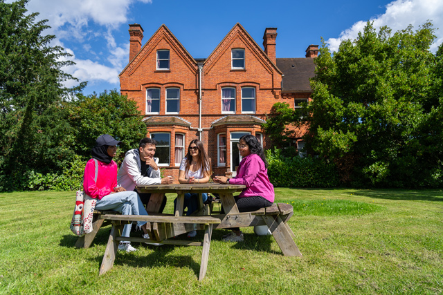 Group of students sat on a picnic bench in the garden