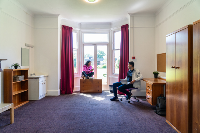 Two students sat talking in a bedroom
