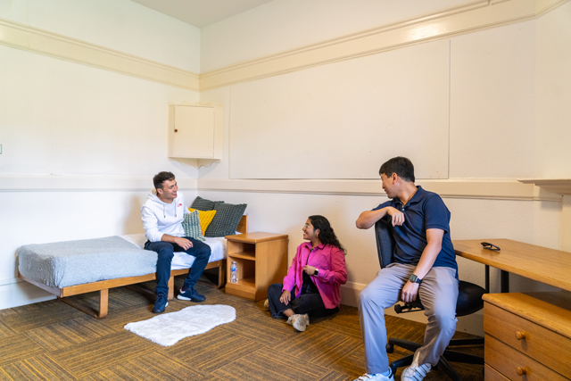 Three students conversing in bedroom