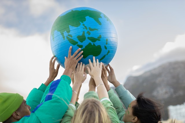 group of people holding up a planet earth ball