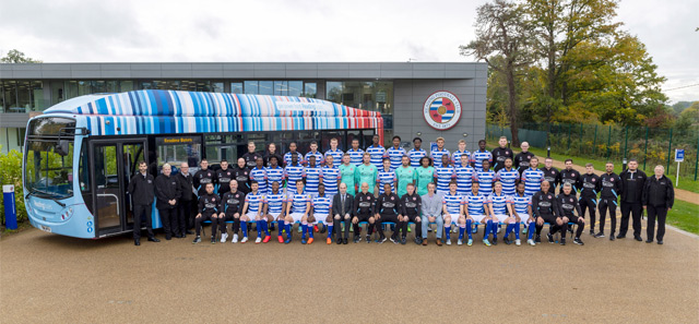 Reading Football Club members standing next to a University of Reading climate stripes bus