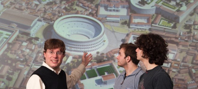 Matthew Nicholls stands in front of a digital reconstruction of Rome